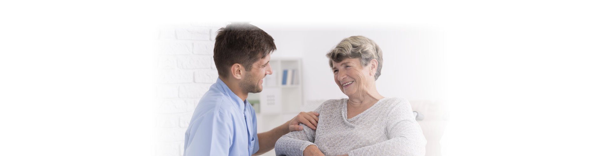 Caregiver comforting smiling elderly women on wheelchair